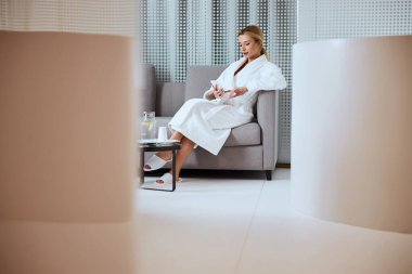 Genç spa müşterisi koltukta aletle oturuyor.