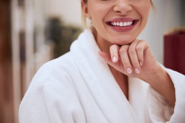 Gülümseyen spa müşterisi terli bir bornoz giyiyor.