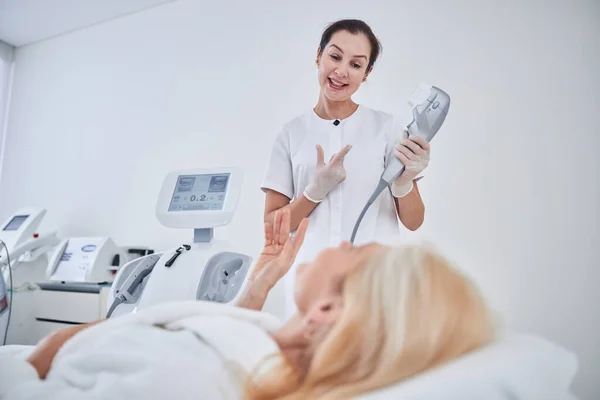 Dos mujeres hablando de la moderna máquina de ultrasonido en el salón de spa de belleza —  Fotos de Stock