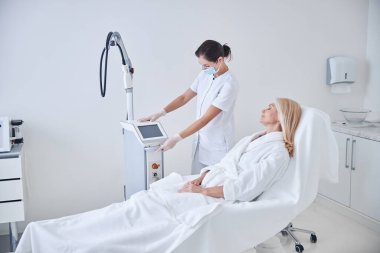 Sarışın beyaz kadın güzellik merkezinde kaplıca tedavisi beklerken güzellik koltuğunda yatıyor.