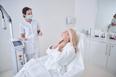 Güzel bir doktor ve çekici bir kadın güzellik kliniğinde cilt prosedürünü tartışıyorlar.