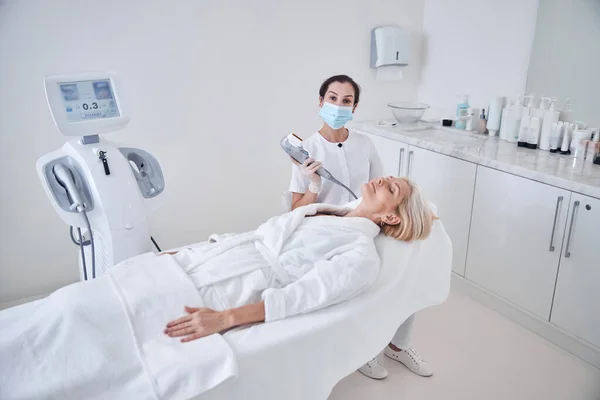 Professional female doctor working with patient while applying special ultrasound machine — Stock Photo, Image