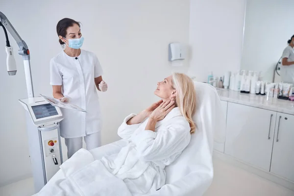 Добре виглядає лікар і чарівна жінка обговорюють процедуру шкіри в клініці краси — стокове фото