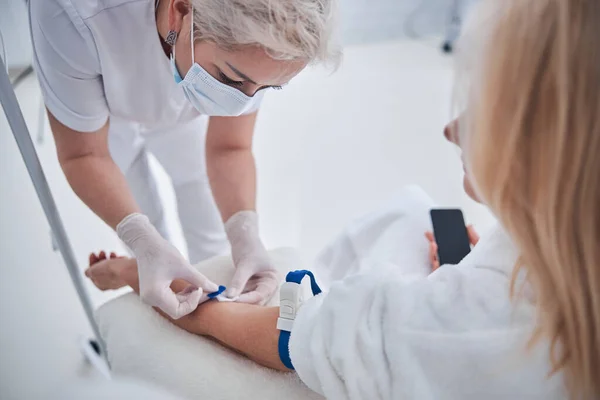 Professional nurse getting treatment vitamin drip for woman in medicine clinic — Stock Photo, Image