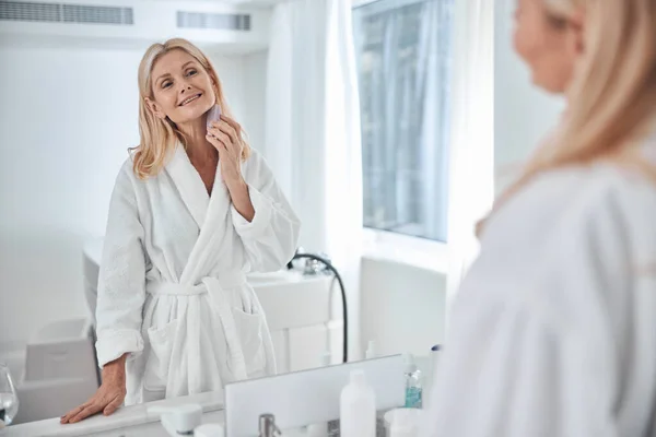 Wanita cantik yang elegan santai dan penuh perhatian wajah kulit di kamar mandi — Stok Foto