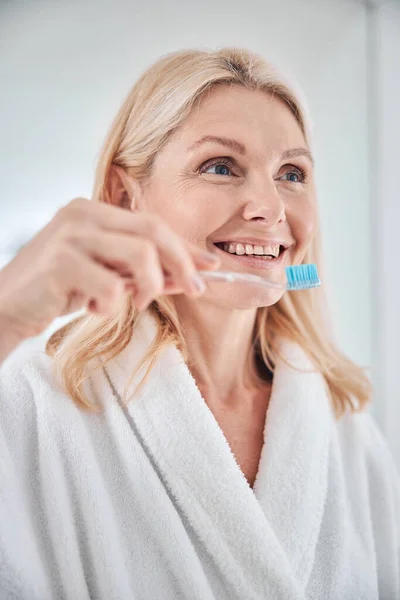 Csinos mosolygós nő vigyáz a fogaira a fürdőszobában. — Stock Fotó