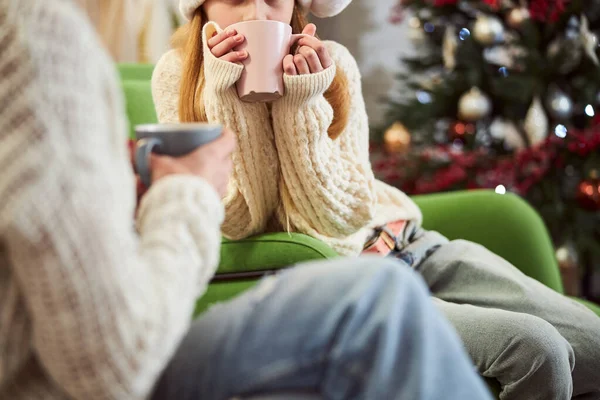 Happy girl drinking tea with mom beside Christmas tree — Stock Photo, Image