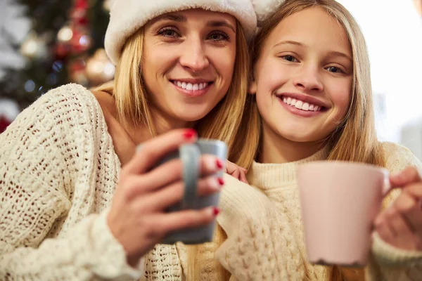 Usmívající se žena s dcerou pije čaj na Silvestra — Stock fotografie