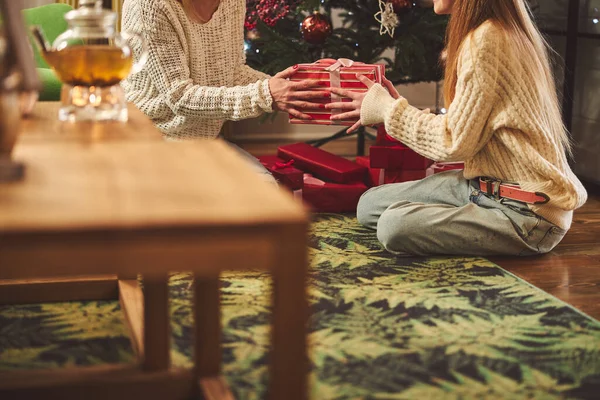 Adolescente chica con madre sentado bajo el árbol de Navidad en el interior —  Fotos de Stock