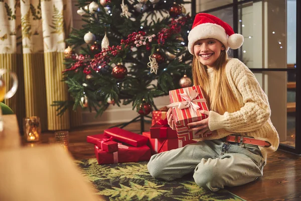 Feliz adolescente sentada en el árbol de Navidad — Foto de Stock