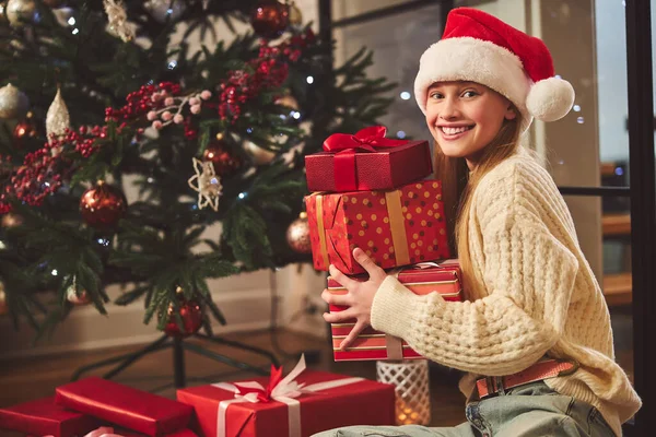 Jovencita alegre regocijándose en el árbol de Navidad en casa —  Fotos de Stock