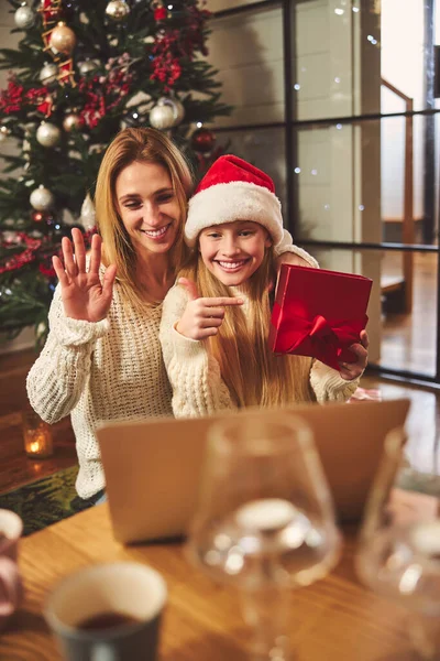 Femme heureuse avec sa fille communiquant avec sa famille en ligne à Noël — Photo