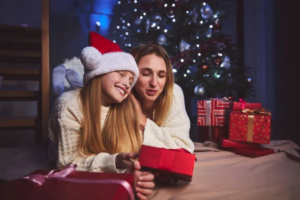 Mujer feliz abrazando a hija amada bajo el árbol de Navidad — Foto de Stock