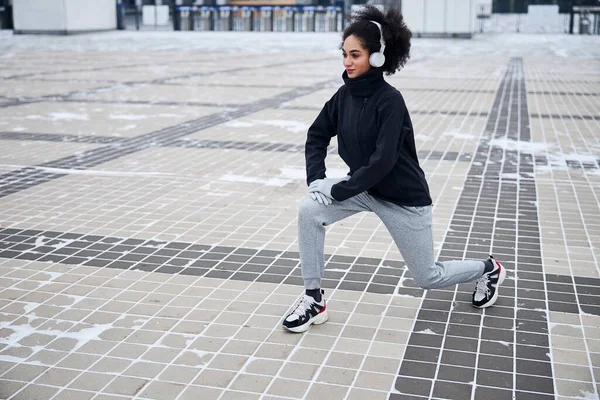 Sportswoman su un quadrato facendo il tratto gamba — Foto Stock