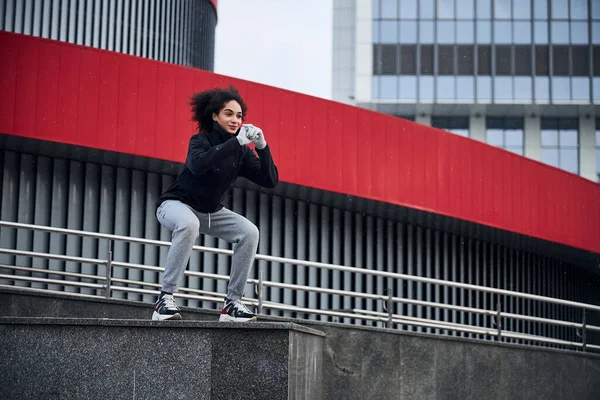 Athletic woman squatting before the parking lot — Stock Photo, Image