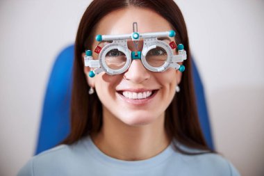 Deneme çerçevesini takan kadın neşeyle gülümsüyor.