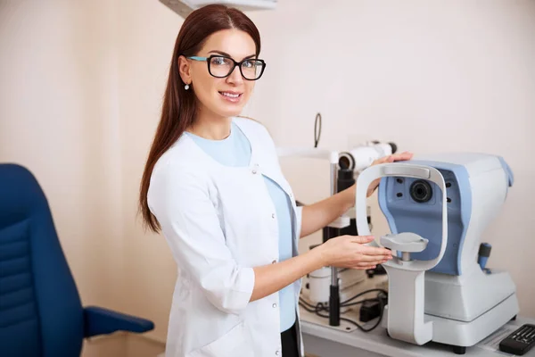Pleased female oculist is touching an autorefractor — Stock Photo, Image