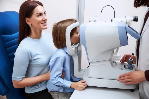 Artsen controleren jongen gezichtsvermogen bij een autorefractor — Stockfoto