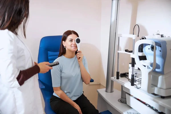 Lady using an occluder while checking her eyesight — Stock Photo, Image