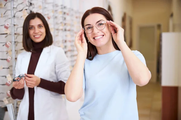Delighted female putting on eyewear with a medical professional — Stock Photo, Image