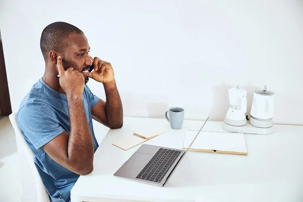 Masculino de raza mixta tapándose la oreja durante una charla telefónica —  Fotos de Stock