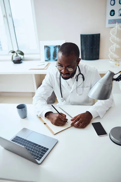 Multietnisk läkare få information på nätet och skriva ner — Stockfoto