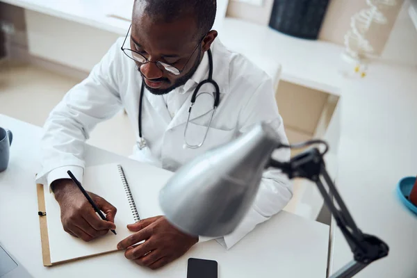 Médico concentrado usando um lápis para registrar informações — Fotografia de Stock