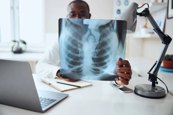 Afro-amerikansk läkare med en röntgen motsatt hans ansikte — Stockfoto