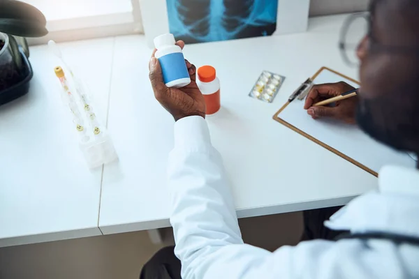 Hombre adulto inspeccionando un envase azul de medicamento — Foto de Stock