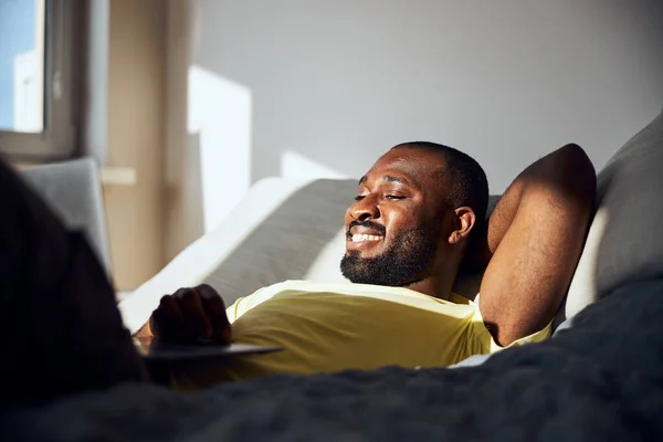 Multiracial homem ter um descanso em uma cama acolhedora — Fotografia de Stock