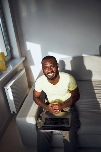 Gemengde-race werknemer naar boven kijkend zittend op zijn bed — Stockfoto