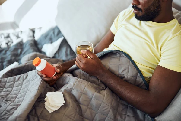 Persoon die een ziekte krijgt en thee drinkt tijdens het studeren van pillen — Stockfoto