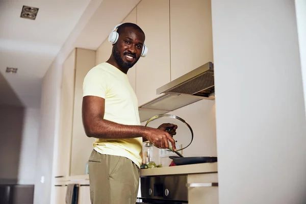 Cozinheiro alegre fritando sua refeição com fones de ouvido em — Fotografia de Stock