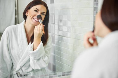 Mutlu kadın sabahları makyaj yapıyor.