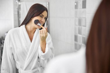 Neşeli güzel kadın evde makyaj yapıyor.