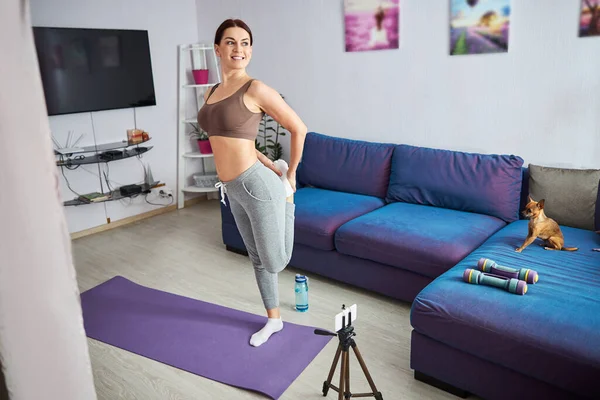 自宅でオンラインワークアウト中に体を暖める女性 — ストック写真