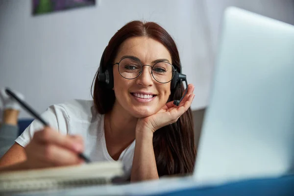 Fröhliche Frauen machen sich bei Online-Konferenz in Innenräumen Notizen — Stockfoto