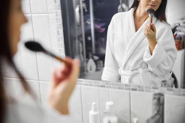 Jolie femme gaie utilisant des cosmétiques pour le visage à l'intérieur — Photo
