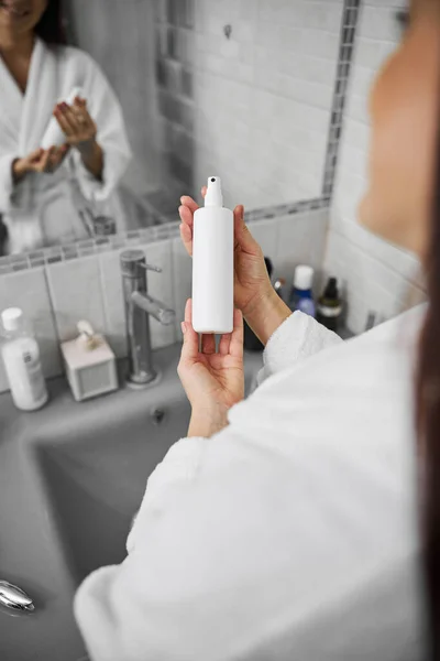 Mujer sonriente usando spray cosmético en el baño — Foto de Stock