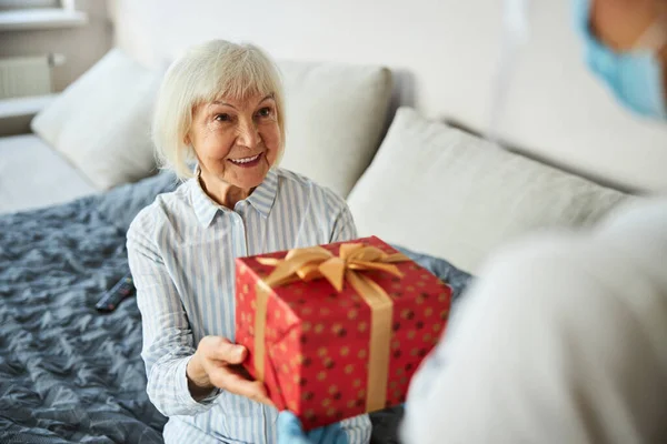Женщина на пенсии берет праздничную упаковку — стоковое фото