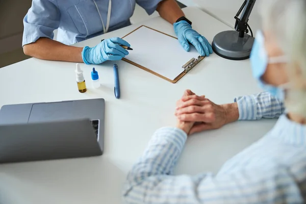 Medische persoon die aantekeningen maakt over de gezondheid van gepensioneerden — Stockfoto