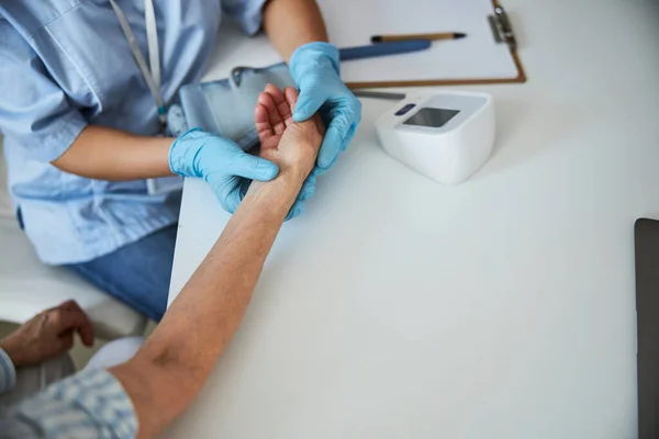 Persona médica sintiendo el pulso de un anciano — Foto de Stock