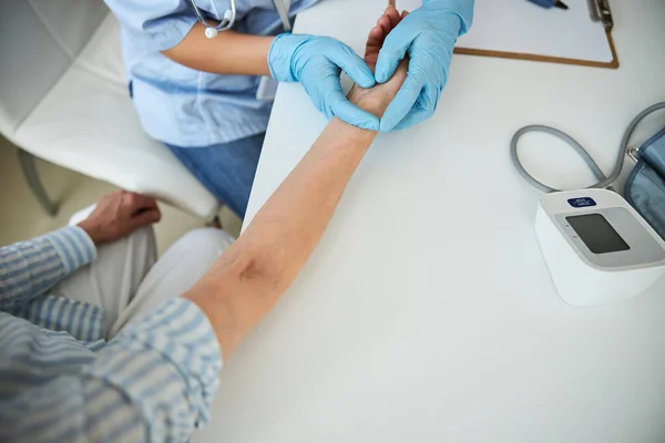 Médico trabalhador pressionando os dedos para uma veia do pulso — Fotografia de Stock