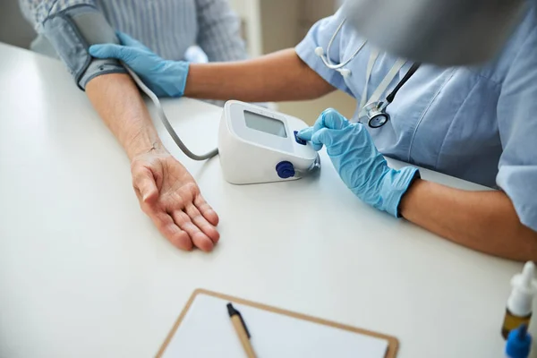 Pessoa médica fazendo uma verificação da pressão arterial feminina idosa — Fotografia de Stock