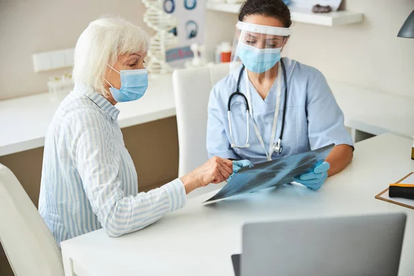 Läkare med en kvinnlig pensionär som tittar på lungröntgen — Stockfoto