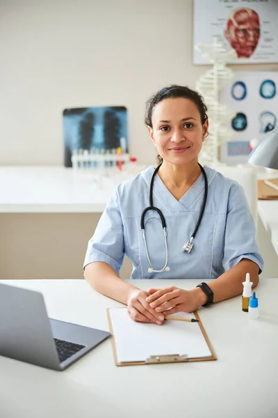 Gesammelte Ärztin faltet ihre Hände auf einem Tisch — Stockfoto