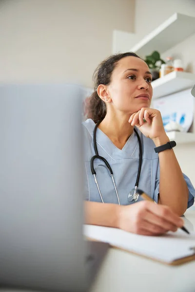 Especialista médico apoyando su barbilla mientras escribe — Foto de Stock