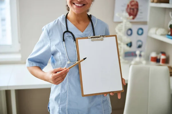Sjukvårdare som pekar en penna mot ett tomt pappersark — Stockfoto