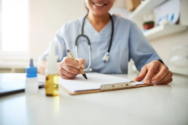 Miljöpenna i händerna på en läkare som skriver på papper — Stockfoto