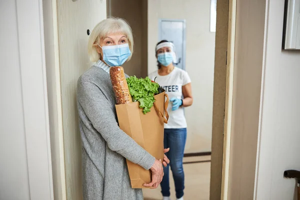 Umsichtige Seniorin und ein junger Hausmeister stehen hinter ihr — Stockfoto